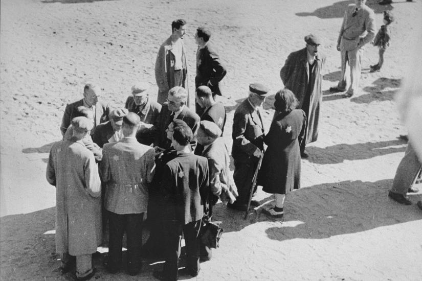 Jews converse outside in the &quot;Sammelstelle&quot; [gathering place] in the Kovno ghetto, 1941 – 1944