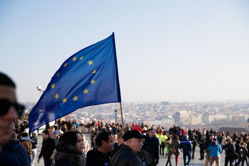 concentration of people in a square, a man is holding a EU flag